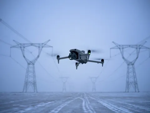 DJI drone hovering in front of high-voltage transmission towers during a power line inspection flight