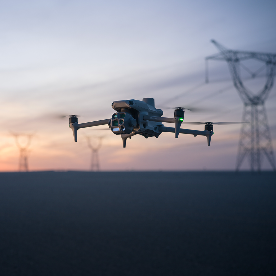 DJI Matrice 4T in flight at dusk near power infrastructure